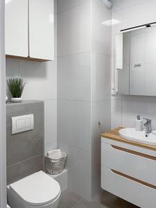 a white bathroom with a toilet and a sink at Apartament Cudovny in Kudowa-Zdrój