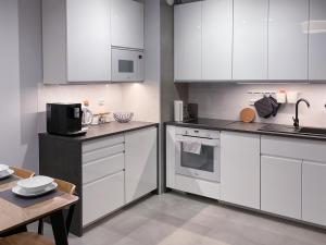 a white kitchen with white cabinets and a table at Apartament Cudovny in Kudowa-Zdrój