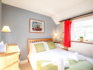 a bedroom with a bed and a window with red curtains at Carnotze in Dorchester