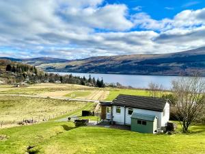 a small house in a field with a lake at Ciaran Cottage in Stron-fearnan