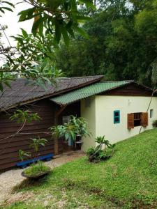 une petite maison avec un toit vert et une cour dans l'établissement Tao da Serra - cabana em meio à natureza!, à São Francisco Xavier
