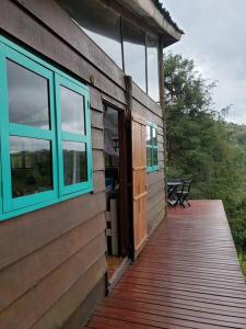 uma casa com janelas azuis e um deque de madeira em Tao da Serra - cabana em meio à natureza! em São Francisco Xavier