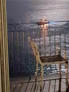 a chair sitting on a balcony looking at the water at Casa Gargano Ravello Amalfi Coast in Amalfi