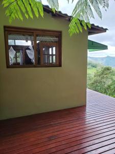 Casa con ventana en una terraza de madera en Tao da Serra - cabana em meio à natureza! en São Francisco Xavier