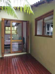 une porte ouverte menant à une chambre dotée d'une terrasse en bois. dans l'établissement Tao da Serra - cabana em meio à natureza!, à São Francisco Xavier
