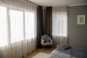a bedroom with a bed and a chair and a window at Māja Rubeņi in Jūrmala
