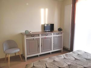 a bedroom with a tv on a cabinet with a chair at Maison Sleep & Swim, 24H Le Mans Classic 2 B&B chambres d'hôtes in Fillé
