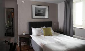 una camera da letto con un letto con lenzuola bianche e cuscini gialli di Hotell Blå Blom a Gustavsberg