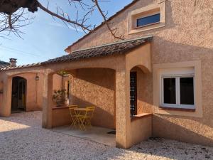 una casa con patio y una silla amarilla al aire libre en AU MIMOSA - Gîte Le Murier, en Passa