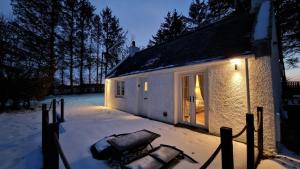 una casa nella neve con la luce accesa di Daisy Cottage - Two bed country retreat a Turriff