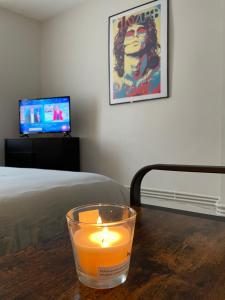 una vela en una mesa con cama y TV en Maison Coconing à Pacy sur Eure, en Pacy-sur-Eure