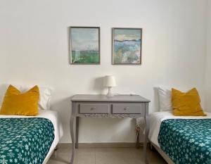 a bedroom with two beds and a table with a lamp at Sea You Soon! in Netanya
