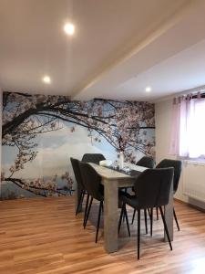 une salle à manger avec une table et une fresque murale dans les arbres dans l'établissement Pension Alice, à Apfelstädt