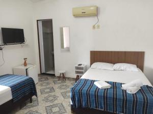a hotel room with two beds and a tv at Pousada Maria Bonita - Piranhas, Alagoas. in Piranhas
