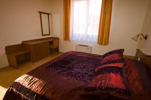 a bedroom with a bed with a red comforter and a window at Szerencsemák Panzió in Kehidakustány +14 photos