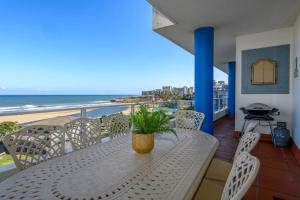 een tafel en stoelen op een balkon met uitzicht op het strand bij 402@ColonialSands in Margate