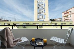 a table and two chairs on a balcony with orange juice at Finn Luxury Suites in Split