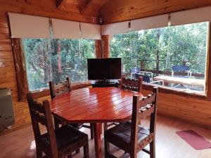 a dining room with a wooden table and a television at Cabaña en Bosque Nativo in San Carlos de Bariloche