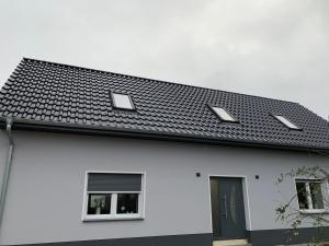 a white house with a black roof and two windows at Haus Benz für 8 Personen - 4 Zimmer m. Dusche Vollausstattung 1km v. Wittenberge Baustelle A14 Parkplätze Grill Gemeinschaftsküche 