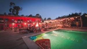 una piscina con mesas y sillas junto a un edificio en Compay Hostel La Pedrera, en La Pedrera