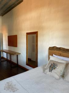 um quarto com uma cama, uma mesa e um espelho em Casa Divinas em Tiradentes