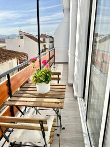 einen Balkon mit einem Holztisch und Blumen darauf in der Unterkunft PISO EN EL CENTRO DE VELEZ MALAGA in Vélez-Málaga