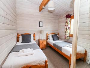 two beds in a room with wooden walls at Snowy Owl Lodge in Rhayader