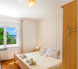 - une chambre avec un grand lit blanc et une fenêtre dans l'établissement Apartments Tatjana Crikvenica, à Crikvenica