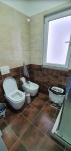 La salle de bains est pourvue de toilettes, d'un lavabo et d'une fenêtre. dans l'établissement luka apartament, à Shëngjin