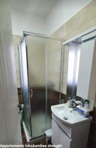 La salle de bains est pourvue d'une douche et d'un lavabo blanc. dans l'établissement luka apartament, à Shëngjin