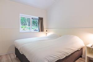 a white bedroom with a large bed and a window at Nesserduinen in Nes