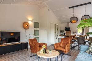 uma sala de estar com um sofá, cadeiras e uma mesa em Nesserduinen em Nes