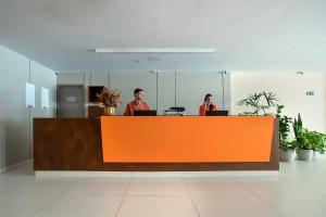 two men sitting at a reception desk in an office at Verano Pajuçara by Tropicalis in Maceió