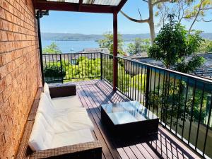 einen Balkon mit einem Sofa und einem Tisch darauf in der Unterkunft Spacious 4BR getaway with panoramic water & mountain view in Green Point