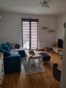 ein Wohnzimmer mit einem blauen Sofa und einem Tisch in der Unterkunft Apartman Tina in Vrnjačka Banja