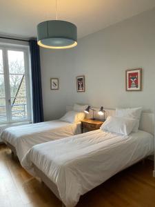 twee bedden in een kamer met een raam bij Bel appartement, bien équipé et confortable dans le centre historique in Fougères