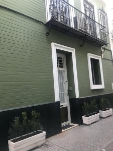 une maison verte avec une porte blanche et un balcon dans l'établissement A 5 minutos de la Catedral, la Giralda y la Maestranza, Sevilla centro, à Séville