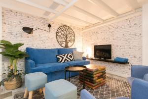 a living room with a blue couch and a brick wall at A 5 minutos de la Catedral, la Giralda y la Maestranza, Sevilla centro in Seville