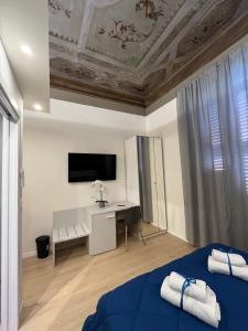 Schlafzimmer mit einem Bett, einem Schreibtisch und einem TV in der Unterkunft La Suite Deluxe Rooms & Apartments in Bologna