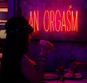 a woman sitting at a table in front of a neon sign at hotel velero cavancha in Iquique