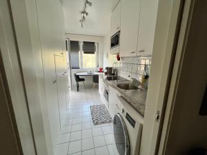 - une cuisine blanche avec un évier et un lave-vaisselle dans l'établissement Agréable appartement près du lac, à Versoix