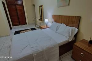 - une chambre avec un grand lit blanc et une tête de lit en bois dans l'établissement Grace Apart Bastos Yaoundé, à Yaoundé