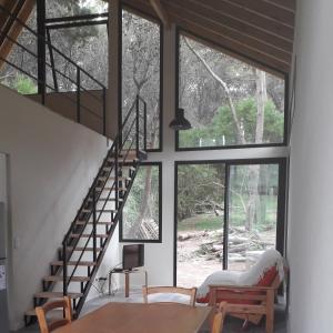 sala de estar con escalera y ventanas en La Bonita Mar Azul en Balneario Mar Azul