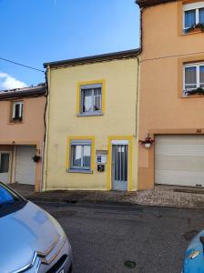 a yellow house with two garage doors on a street at Résidence L'Alexandra 2 étoiles in Bourbonne-les-Bains