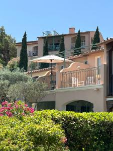 a large building with an umbrella and some bushes at AZUR APPARTEMENT (SEA VIEW) LES RESTANQUES DE ST-TROPEZ1131 in Grimaud