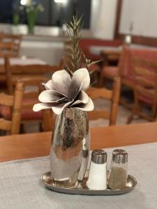 Mike‘s Mosel Lodge في تريس كاردن: مزهرية مع وردة على صحن على طاولة
