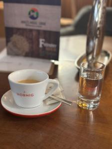 a cup of coffee and a glass of water on a table at Mike‘s Mosel Lodge in Treis-Karden