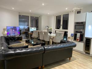 a living room with a black leather couch and a table at Luxury Apartment North Greenwich London in London