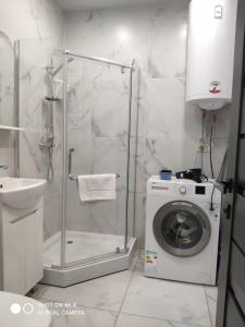 a bathroom with a washing machine and a shower at Apartments Domovik Миру 11с /11 in Mukacheve