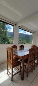 a wooden table and chairs in a room with windows at Casa Vista para Serra in Tiradentes
